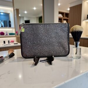 Shimmy black cosmetics bag with a lipstick and perfume bottle on zipper pull